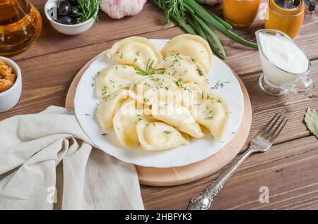 Knödel mit Kartoffeln auf einem weißen Teller auf einem dunklen Holzhintergrund Stockfoto