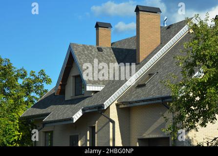 Ein Haus mit einer Dachschräge mit Asphaltschindeln installiert, Dachfenster, Oberlichter, Soffit und Faszien Boards, Lüftung, zwei Bric Stockfoto