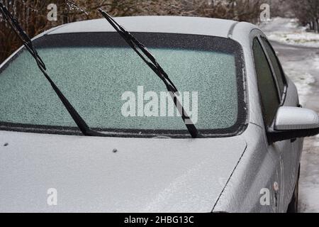 Ein gefrorenes Auto mit einer Nahaufnahme einer gefrorenen Windschutzscheibe, Windschutzscheibe nach eisigen Regenfällen mit Eis bedeckt, Eissturm im Winter. Stockfoto