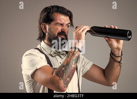 Auf der Suche nach dem letzten Tropfen. Brutaler Barkeeper in Fliege. Eleganter Barkeeper. Hübscher Hipster, der Weinglas trinkt. Sommelier, der Alkohol schmeckte Stockfoto