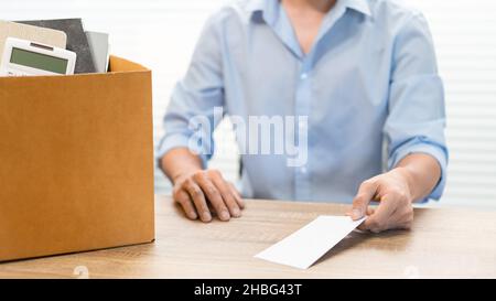 Resignation Concept der männliche Offizier sitzt, legt seine Kiste seiner gehört auf den Schreibtisch und übergibt den weißen Brief an jemanden. Stockfoto