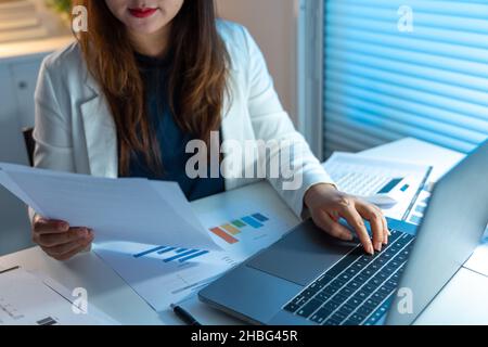 Überarbeitungs-Konzept die Frau, die ihre Arbeit spät in der Nacht macht, indem sie Papiere liest und sie auf das Notizbuch schreibt. Stockfoto