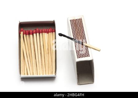 Nahaufnahme der Streichholzschachtel mit vielen neuen Streichhölzern und einem verbrannten Streichholz auf der Reibefläche, isoliert auf weißem Hintergrund Stockfoto