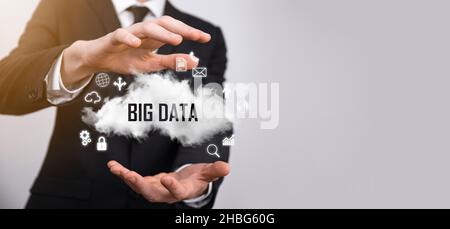 Geschäftsmann hält die Inschrift , Wort BIG DATA . Vorhängeschloss, Gehirn, Mann, Planet, Graph, Lupe, Zahnräder, Symbol für Cloud, Grid, Dokument, Brief, Telefon Stockfoto