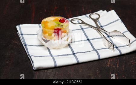 Kuchen mit Gelee, Kiwi, Kirschen und Mango auf dem Tisch. Leckeres Mini-Dessert auf einem hölzernen Hintergrund, Nahaufnahme. Stockfoto