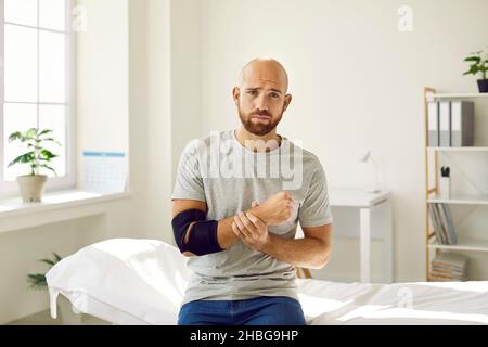 Porträt eines traurigen Mannes, der nach einem Knochenbruch einen Verband am Arm tragen muss. Stockfoto
