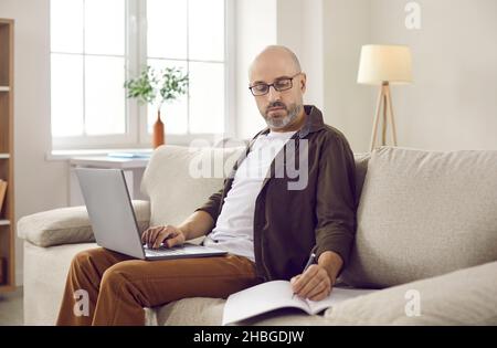 Ein Mann mittleren Alters arbeitet weit entfernt vom Heimbüro auf einem Laptop Stockfoto