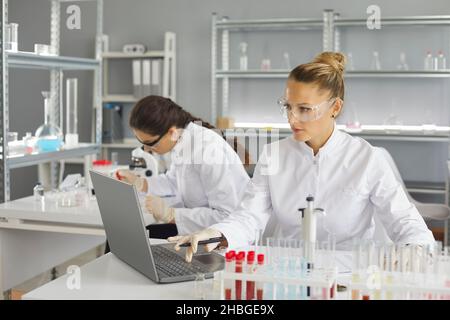 Wissenschaftler, die im modernen Pharmalabor forschen und an einem Laptop arbeiten Stockfoto