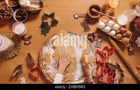 Lebkuchen zu Hause machen. Kleines Mädchen, das Kekse aus Lebkuchenteig schneidet. Weihnachts- und Neujahrstraditionen Konzept. Weihnachtsbäckerei. Glücklich Stockfoto