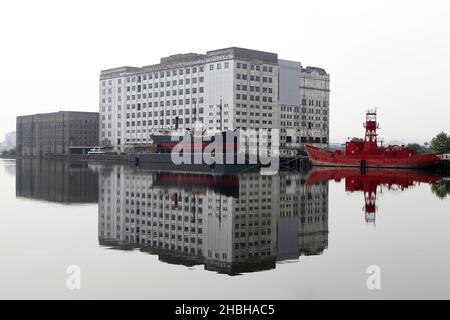 Blick auf gebrauchte Lagerhäuser und moderne Wohnungen und Boote vom Royal Victoria Dock, Excel in East London. Stockfoto