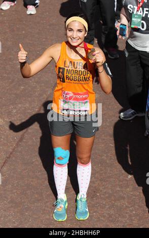 Laura White mit Medaille auf der Ziellinie des Virgin Money London Marathon auf der Mall in London. Stockfoto