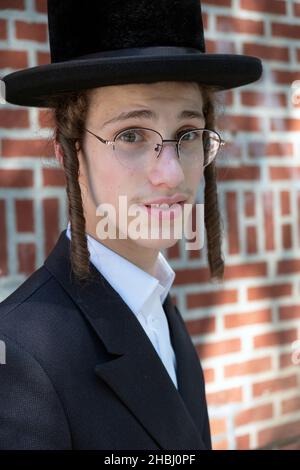 Kopf- und Schulterporträt eines chassidischen Teenagers mit langem lockigen Peyot. In Williamsburg, Brooklyn, New York City. Stockfoto