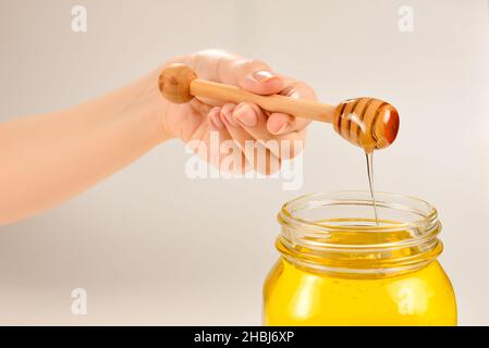 Dipper mit Honig in Frauenhand. Platz für Text oder Design. Stockfoto