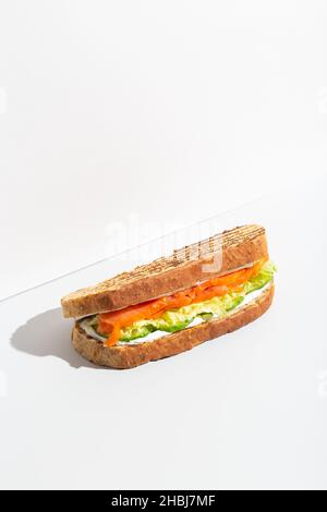 Sandwich mit Lachs, Käse und Salat auf grauem dunklen Schatten Stockfoto
