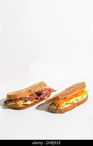 Zwei Sandwiches mit Lachs, Schinken, Käse und Salat auf grauem dunklen Schatten Stockfoto