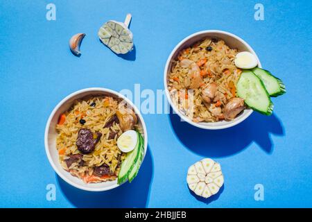 Traditionelle usbekische orientalische Küche Reis mit Fleisch Plov auf blauem Haar Schatten modernen Stil. Stockfoto