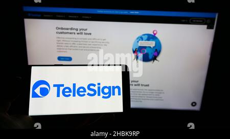 Person, die ein Mobiltelefon mit dem Logo des US-amerikanischen Kommunikationsunternehmens TeleSign Corporation auf dem Bildschirm vor der Webseite hält. Konzentrieren Sie sich auf die Telefonanzeige. Stockfoto