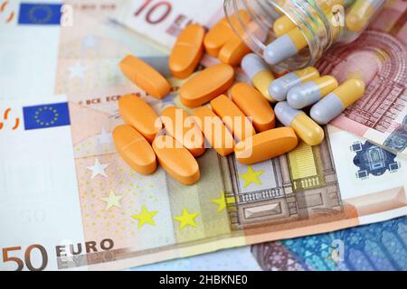 Pillen und Kapseln aus einer Flasche auf Euro-Banknoten verteilt. Konzept der Gesundheitsversorgung in der EU, Pharmageschäft, Arzneimittelpreise, Apotheke Stockfoto