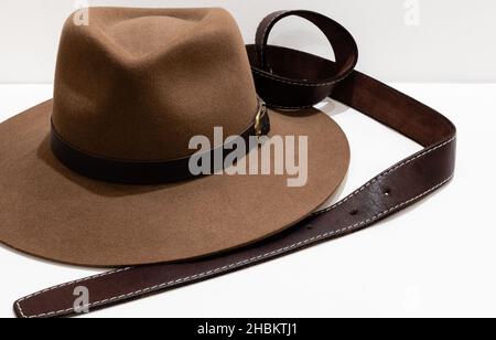 Klassischer Cowboy-Filzhut in Braun und Ledergürtel auf weißem Hintergrund Stockfoto