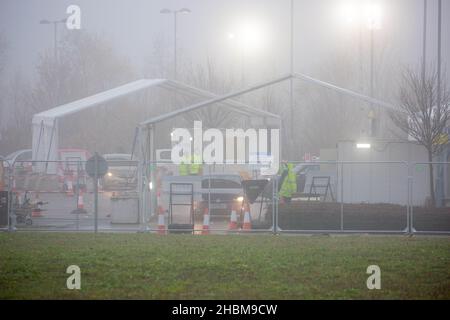 Das Bild vom 19th 2021. Dezember zeigt die geschäftige Fahrt durch das Testzentrum in Milton, Cambridge, unter Flutlicht an einem nebligen Sonntagmorgen, während die Leute zu ihren PCR-Tests gehen. Mit der Zunahme der Omicron-Fälle steigt die Nachfrage nach Tests, da einige Personen keinen Platz für einen Test buchen oder Testkits zu Hause erhalten können. Stockfoto