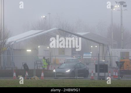 Das Bild vom 19th 2021. Dezember zeigt die geschäftige Fahrt durch das Testzentrum in Milton, Cambridge, unter Flutlicht an einem nebligen Sonntagmorgen, während die Leute zu ihren PCR-Tests gehen. Mit der Zunahme der Omicron-Fälle steigt die Nachfrage nach Tests, da einige Personen keinen Platz für einen Test buchen oder Testkits zu Hause erhalten können. Stockfoto