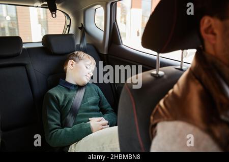 Porträt eines Jungen im Teenageralter, der auf dem Rücksitz des Familienwagens schläft, Platz zum Kopieren Stockfoto