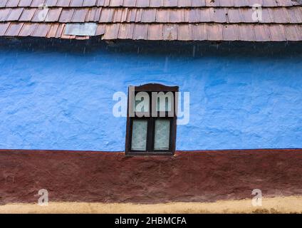 Holzfenster auf einer bunten Wand eines rustikalen traditionellen kleinen Lehmhauses in der ländlichen Landschaft, an regnerischen Tagen, in Salaj County, Siebenbürgen, Roma Stockfoto