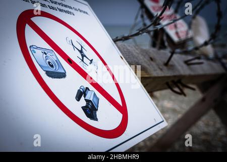 Kein Foto, Video oder Drohnen erlaubt Schild mit rotem Kreis in durch den Strand mit verdrahteten Zaun auf dem Hintergrund beschränkt. KEINE GO-Zone. Stockfoto