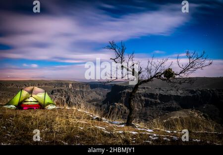 Grünes Zelt am Rand der Klippe mit dem Hintergrund der Schlucht des Ihlara-Tals und dem wilden Baum und Schnee um. Aktivitäten und Trekking i Stockfoto