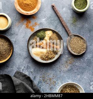 Draufsicht auf eine Auswahl an trockenen Gewürzen, die zur Herstellung einer griechischen Würze verwendet wurden. Stockfoto