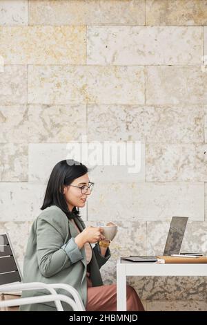 Vertikale Seitenansicht Porträt der jungen Geschäftsfrau in Online-Treffen im Café im Freien Stockfoto