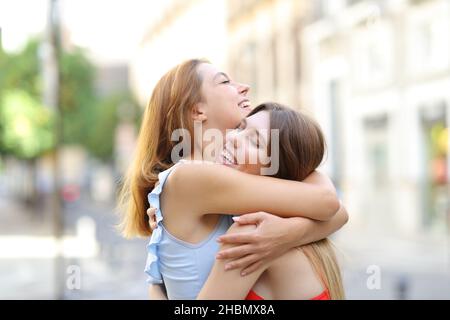 Zwei aufgeregte Freunde umarmen sich und treffen sich auf der Straße Stockfoto