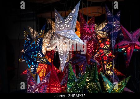 Leuchtende Weihnachtssterne aus Papier in verschiedenen Farben in einem Marktstand gefaltet, Laterne für die dunklen Winterferien, Kopierraum, ausgewählter Fokus, nar Stockfoto