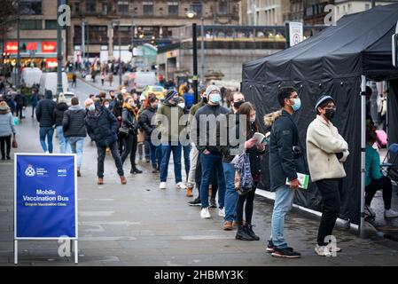 An der Waverley Bridge in Edinburgh stehen die Menschen für den mobilen Impfbus an, da das Impfprogramm für Coronaviren auf ein bisher unerreichtes Tempo anläuft, wobei jedem in Frage kommenden Erwachsenen in Schottland bis Ende Dezember eine Nachspritze angeboten wird. Bilddatum: Montag, 20. Dezember 2021. Stockfoto