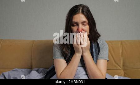 Depressive Frau mit laufender Nase sitzt auf dem Sofa im Wohnzimmer Stockfoto