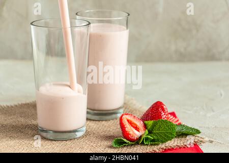 Milchshake in hohen Gläsern, Erdbeeren, Minze, Cocktail in ein Glas gegossen Stockfoto