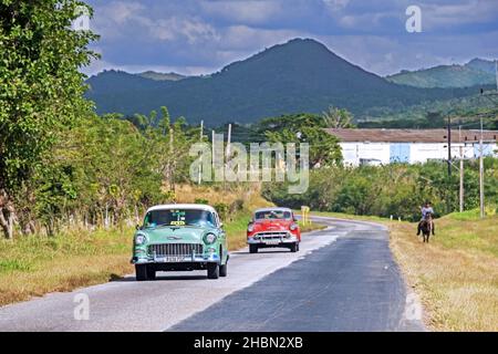 Altes Chevrolet-Taxi und rotes klassisches amerikanisches Auto fahren entlang der Circuito Sur / CS, West-Ost-Autobahn in der Provinz Cienfuegos auf der Insel Kuba Stockfoto