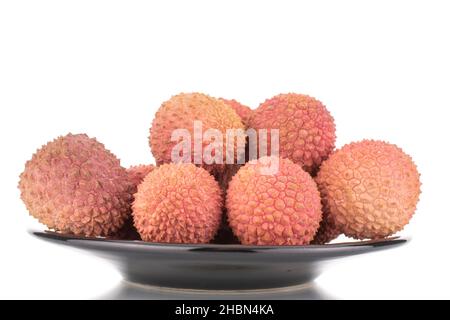 Mehrere saftige süße Litschi-Früchte auf einer Keramikplatte, Nahaufnahme, isoliert auf Weiß. Stockfoto