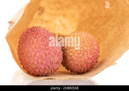 Zwei reife Bio-Litchi-Früchte mit Papiertüte, Nahaufnahme, isoliert auf Weiß. Stockfoto