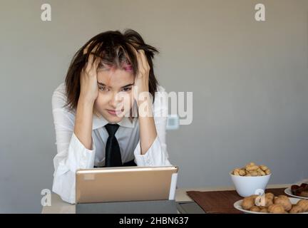 Frau mit den Händen auf dem Kopf frustriert vor ihrem Tablet und starrte auf die Kamera Stockfoto