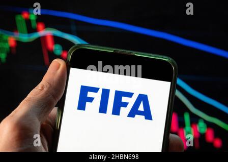 China. 09th Dez 2021. Auf dieser Fotolabbildung ist das Logo der Fédération Internationale de Football Association (FIFA) zu sehen, das auf einem Smartphone mit einer Indexgrafik der wirtschaftlichen Börse im Hintergrund zu sehen ist. (Foto von Budrul Chukrut/SOPA Images/Sipa USA) Quelle: SIPA USA/Alamy Live News Stockfoto