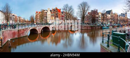 Panorama des Amsterdamer Kanals Keizersgracht mit typischen holländischen Häusern und Brücke während der morgendlichen blauen Stunde, Holland, Niederlande Stockfoto