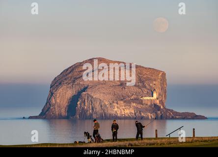 Männer, die in der Abenddämmerung auf dem Golfplatz Glen, North Berwick, vor Bass Rock, Firth of Forth, Schottland, Großbritannien, Golf spielen Stockfoto