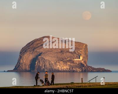 Männer, die in der Abenddämmerung auf dem Golfplatz Glen, North Berwick, vor Bass Rock, Firth of Forth, Schottland, Großbritannien, Golf spielen Stockfoto