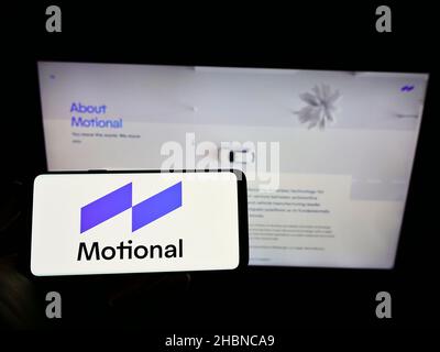 Person, die Mobiltelefon mit dem Logo des US-Autonomous Vehicle Company Motional Inc. Auf dem Bildschirm vor der Business-Webseite hält. Konzentrieren Sie sich auf die Telefonanzeige. Stockfoto