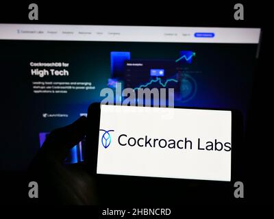 Person, die das Smartphone mit dem Logo der US-SQL-Datenbankfirma Cocockroach Labs Inc. Auf dem Bildschirm vor der Website hält. Konzentrieren Sie sich auf die Telefonanzeige. Stockfoto