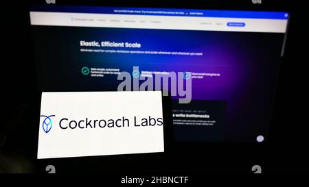 Person, die Mobiltelefon mit dem Logo des US-SQL-Datenbankunternehmens Cockroach Labs Inc. Auf dem Bildschirm vor der Business-Webseite hält. Konzentrieren Sie sich auf die Telefonanzeige. Stockfoto