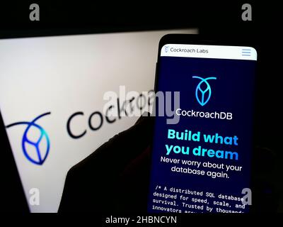 Person, die Smartphone mit Website der US-SQL-Datenbank-Firma Cockroach Labs Inc. Auf dem Bildschirm vor dem Logo hält. Konzentrieren Sie sich auf die Mitte des Telefondisplays. Stockfoto
