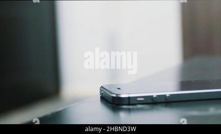 Nahaufnahme von Young man Hand stellt Handy auf Holztisch. Handy auf Holztisch legen. Menschliche Hand legt auf Tisch Handy mit comple Stockfoto
