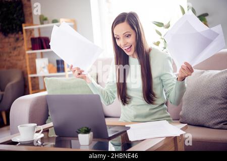 Foto von funky Millennial Brünette Dame sitzen auf Sofa Arbeit Laptop tragen blaues Hemd zu Hause allein Stockfoto